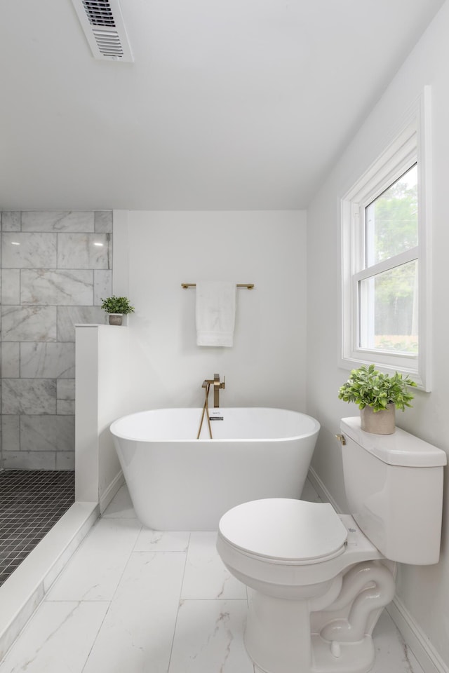 bathroom with a walk in shower, marble finish floor, a freestanding tub, toilet, and visible vents