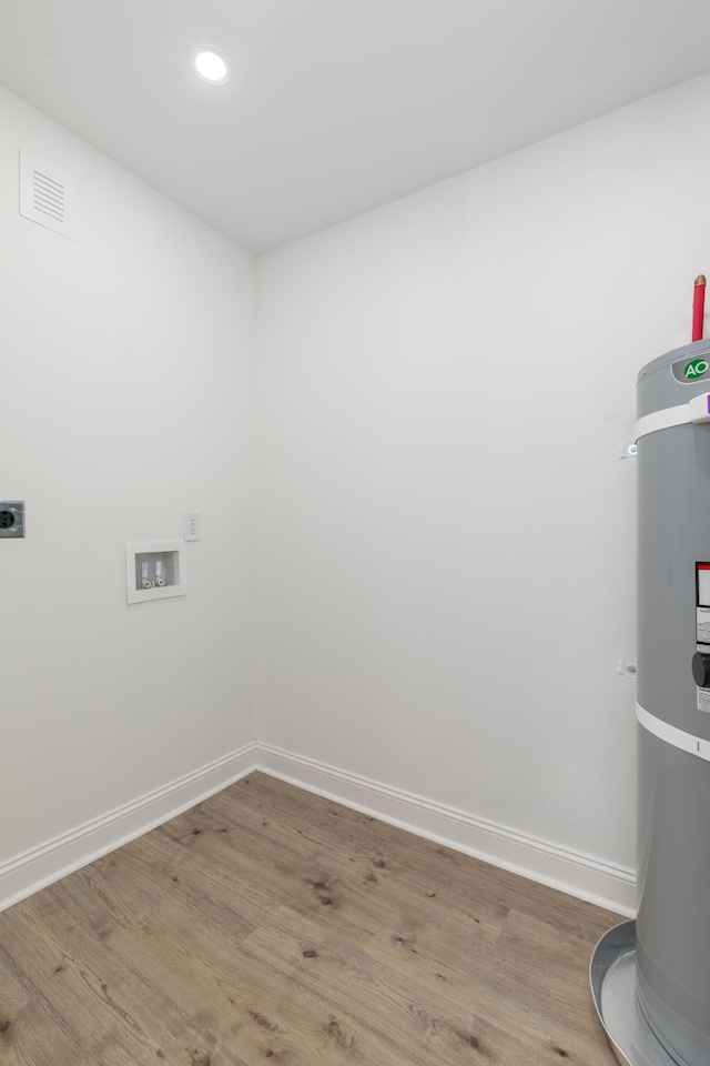 clothes washing area with secured water heater, laundry area, electric dryer hookup, baseboards, and wood finished floors