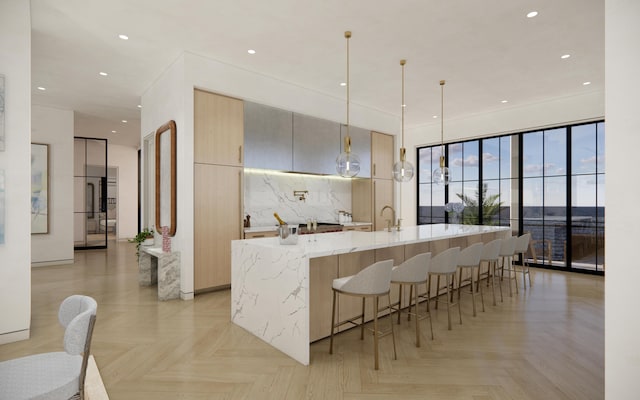 kitchen featuring modern cabinets, light stone countertops, recessed lighting, a breakfast bar area, and a spacious island