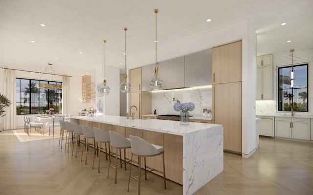 kitchen with a kitchen breakfast bar, light stone countertops, decorative light fixtures, light parquet flooring, and a large island