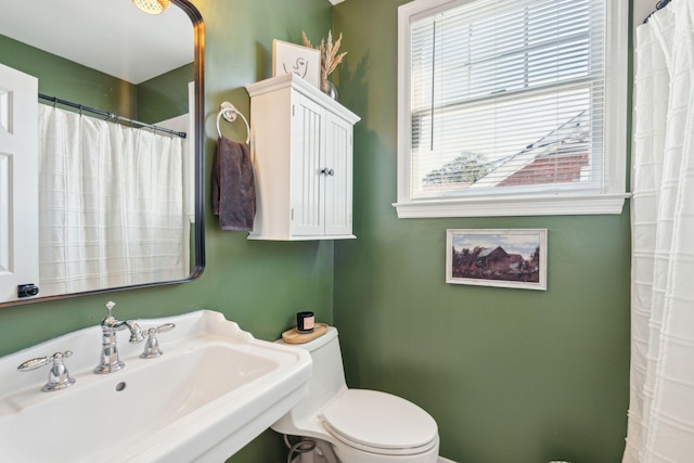 bathroom with toilet, a healthy amount of sunlight, and sink