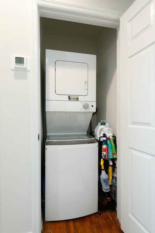 laundry area with stacked washer and dryer and dark hardwood / wood-style flooring