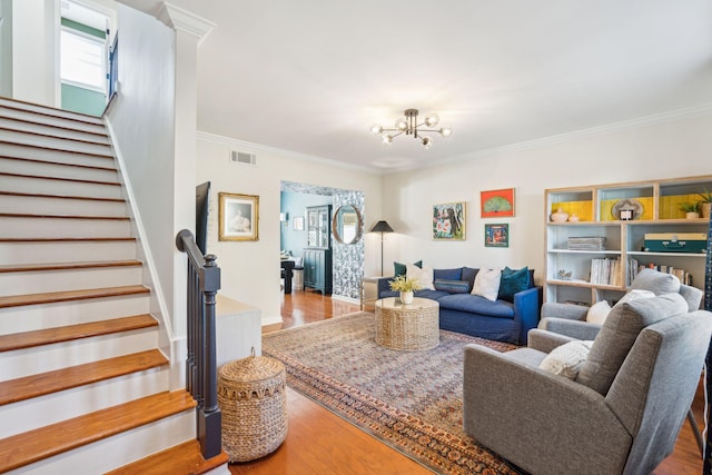 living room featuring wood-type flooring, ornamental molding, and an inviting chandelier