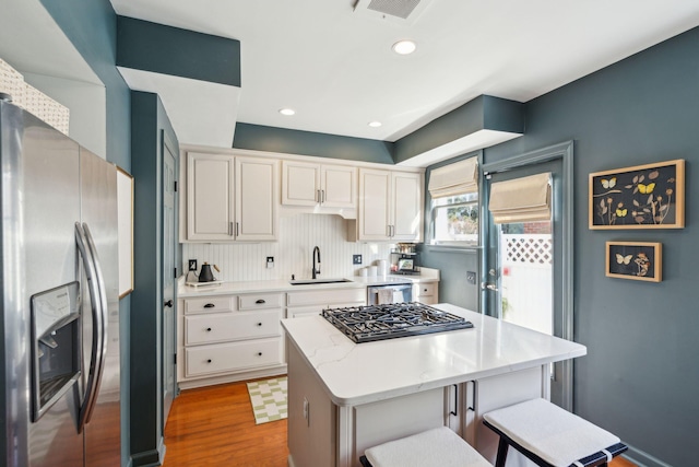 kitchen with a center island, a breakfast bar, sink, hardwood / wood-style flooring, and stainless steel appliances