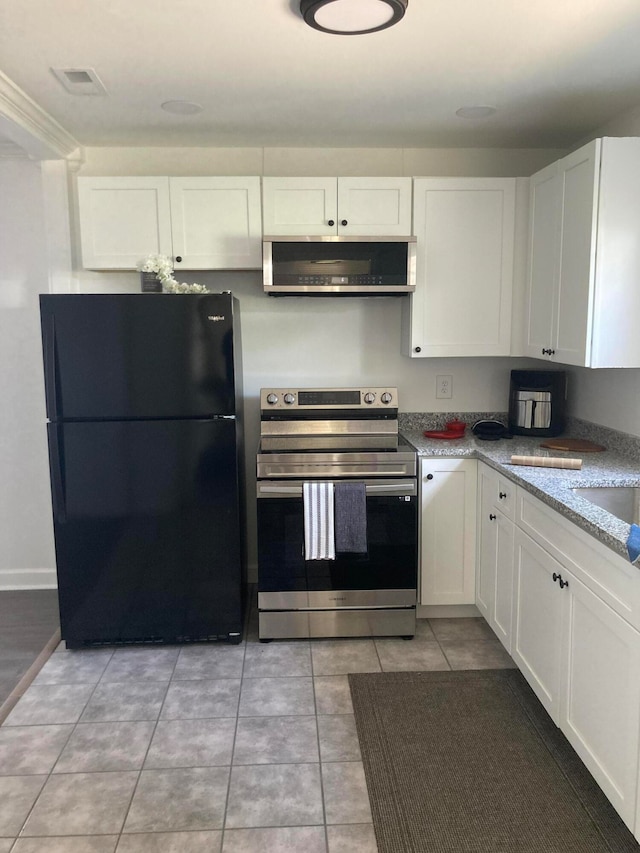 kitchen featuring white cabinets, exhaust hood, black fridge, and stainless steel electric stove