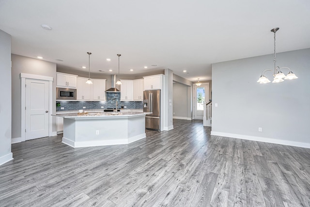 kitchen featuring appliances with stainless steel finishes, pendant lighting, light hardwood / wood-style floors, and wall chimney exhaust hood