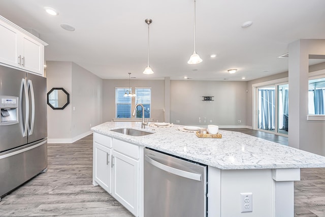 kitchen featuring white cabinetry, sink, stainless steel appliances, light hardwood / wood-style flooring, and an island with sink