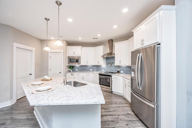 kitchen featuring sink, wall chimney range hood, wood-type flooring, a kitchen island with sink, and appliances with stainless steel finishes