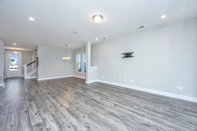 unfurnished living room featuring wood-type flooring and an inviting chandelier