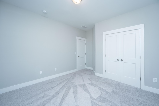 unfurnished bedroom with light colored carpet and a closet