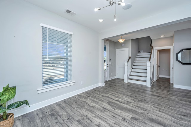 unfurnished living room featuring hardwood / wood-style flooring and a chandelier