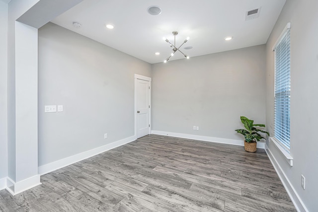 empty room featuring light wood-type flooring and an inviting chandelier