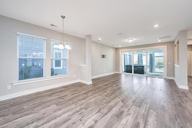 unfurnished living room featuring hardwood / wood-style floors and an inviting chandelier