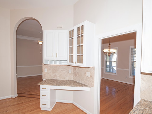 kitchen with tasteful backsplash, light stone countertops, white cabinets, and light hardwood / wood-style floors