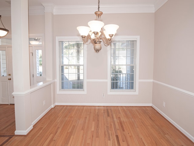 unfurnished dining area featuring light hardwood / wood-style floors, an inviting chandelier, and crown molding