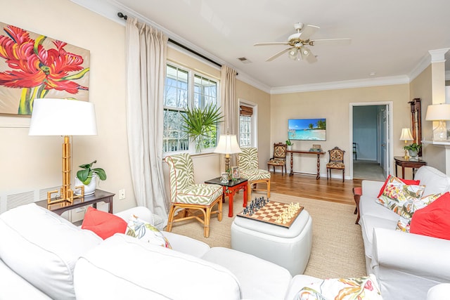 living room featuring a ceiling fan, visible vents, crown molding, and wood finished floors