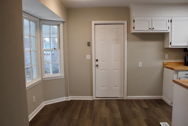 kitchen featuring butcher block countertops, dark hardwood / wood-style flooring, white cabinets, and a wealth of natural light