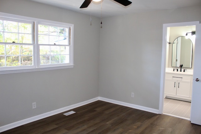 unfurnished bedroom with ceiling fan, sink, dark wood-type flooring, and ensuite bath