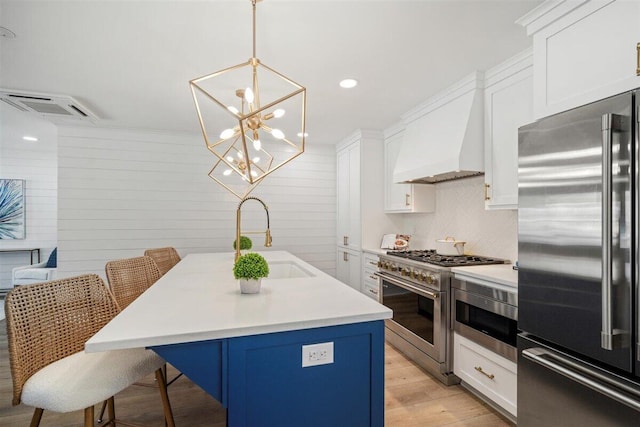 kitchen with premium appliances, a breakfast bar, light countertops, and a center island with sink