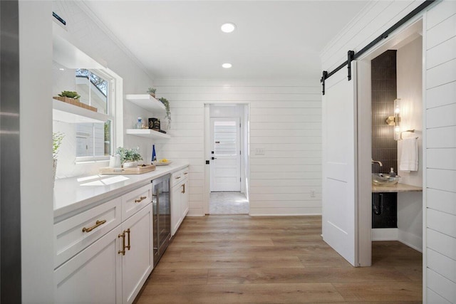 kitchen with a barn door, wine cooler, white cabinets, light countertops, and open shelves