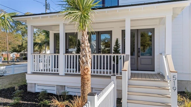 property entrance with covered porch and fence