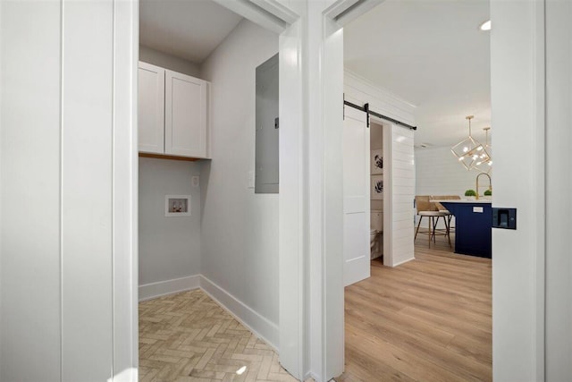 washroom featuring washer hookup, cabinet space, light wood-style flooring, a barn door, and baseboards