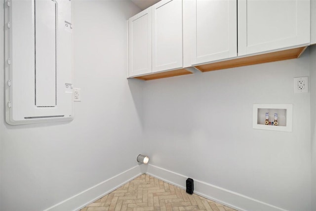 clothes washing area with cabinet space, baseboards, and washer hookup