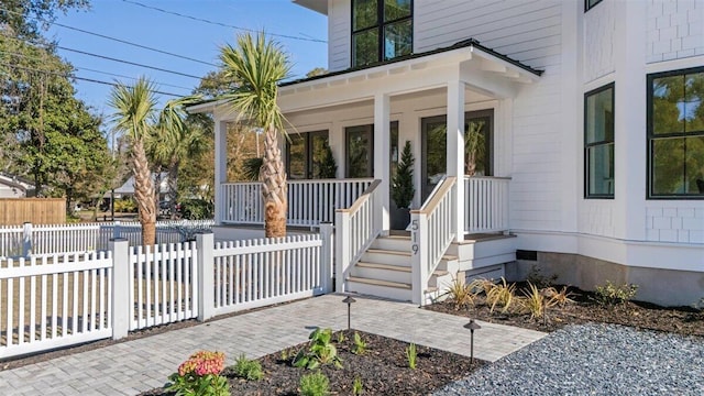 doorway to property featuring a porch and fence