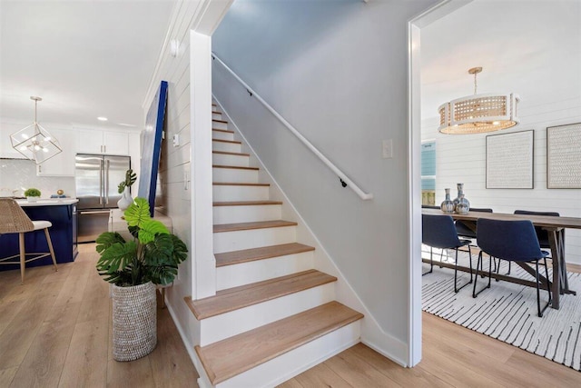 stairs with an inviting chandelier and wood finished floors