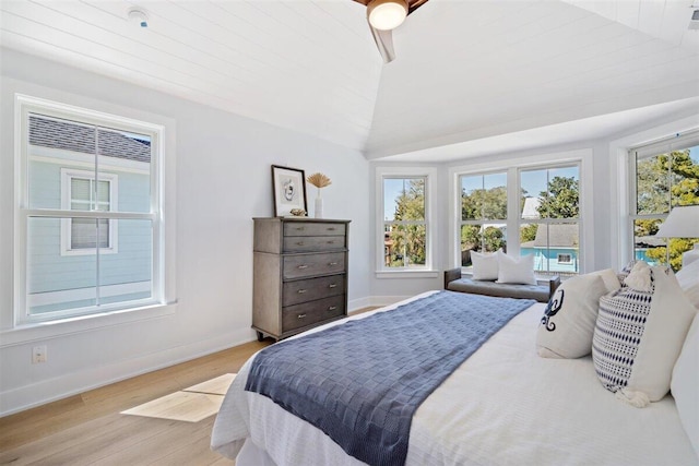 bedroom with lofted ceiling, multiple windows, light wood-type flooring, and baseboards