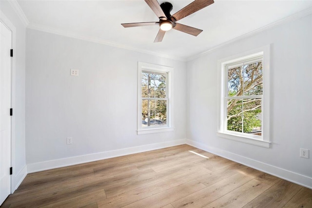 spare room featuring light wood finished floors, ornamental molding, and baseboards