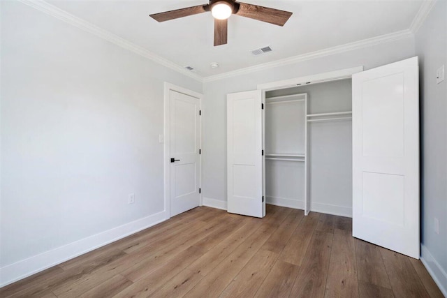 unfurnished bedroom featuring a closet, visible vents, light wood-style flooring, ornamental molding, and baseboards