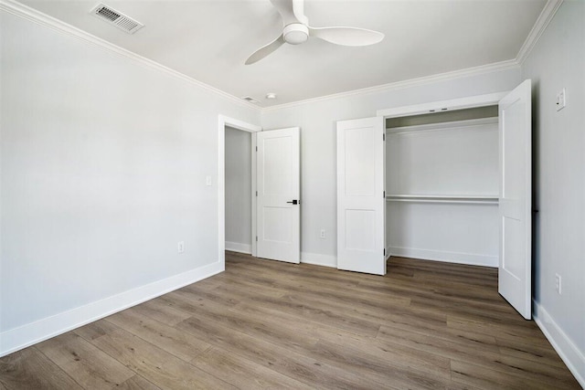 unfurnished bedroom featuring baseboards, crown molding, visible vents, and wood finished floors