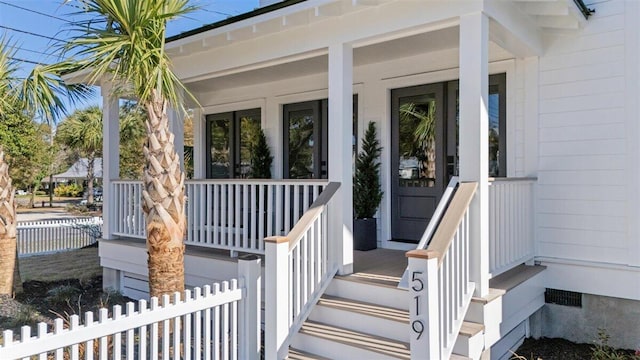 doorway to property featuring a porch, crawl space, and fence