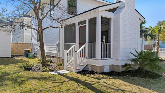 exterior space with central air condition unit, a sunroom, fence, and a yard