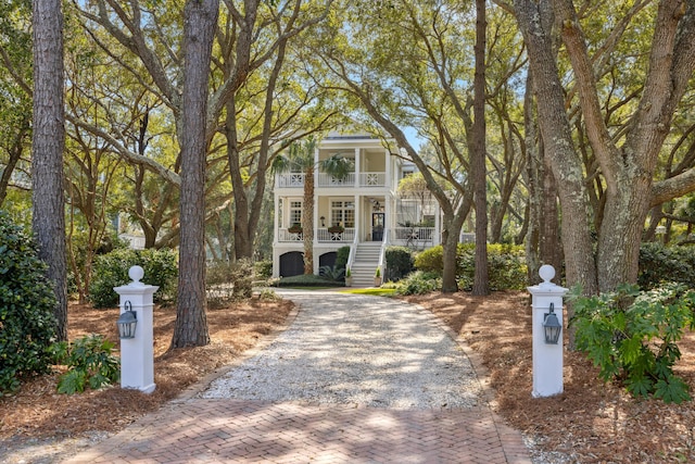 view of front of home with covered porch, stairs, and decorative driveway