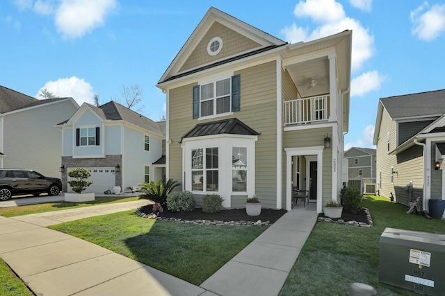 view of front facade featuring a standing seam roof, a front yard, metal roof, a balcony, and ceiling fan