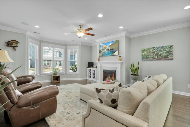 living room with ornamental molding, a glass covered fireplace, wood finished floors, recessed lighting, and baseboards