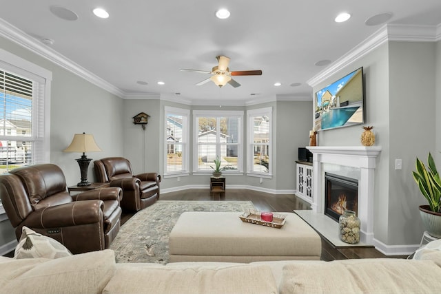 living area with a wealth of natural light, a fireplace, wood finished floors, and ornamental molding