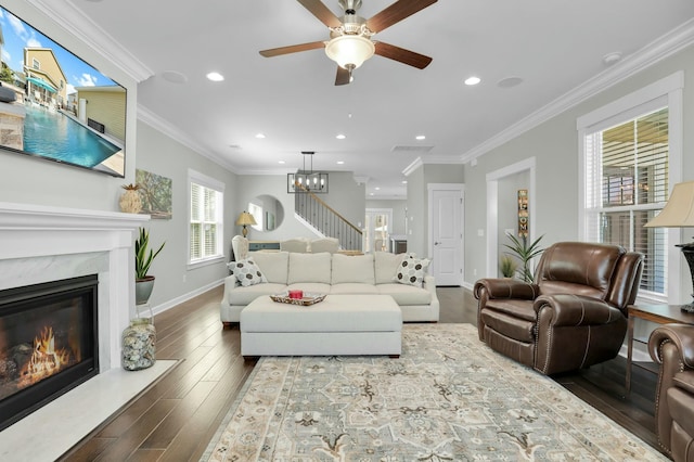 living area featuring a fireplace, stairs, crown molding, and wood finished floors