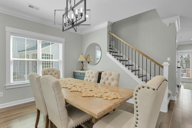 dining room with visible vents, crown molding, baseboards, stairway, and wood finished floors