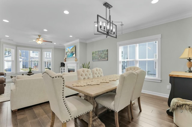 dining space featuring dark wood-type flooring, a lit fireplace, and ornamental molding