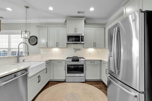 kitchen with a sink, ornamental molding, visible vents, and stainless steel appliances