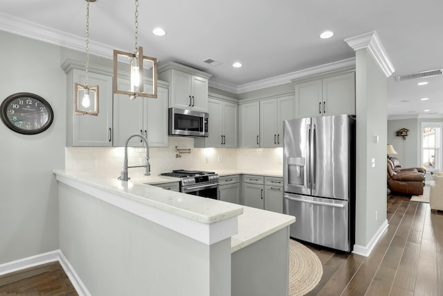 kitchen featuring visible vents, dark wood finished floors, ornamental molding, a peninsula, and stainless steel appliances