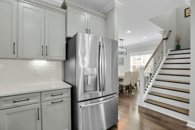 kitchen with ornamental molding, backsplash, dark wood-style floors, stainless steel fridge, and light countertops