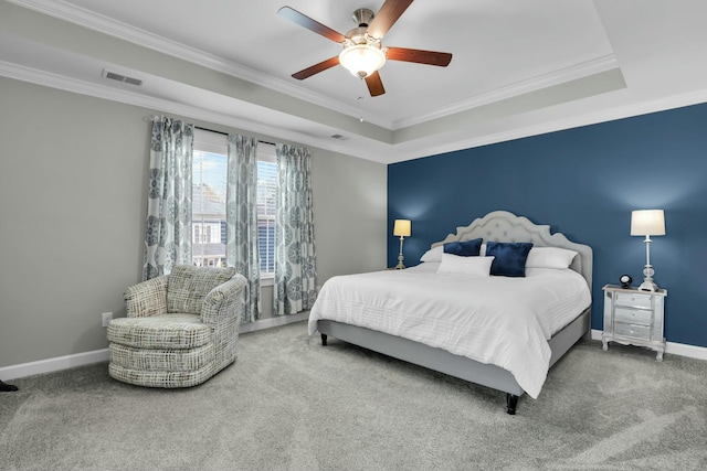 carpeted bedroom featuring crown molding, baseboards, visible vents, and a tray ceiling