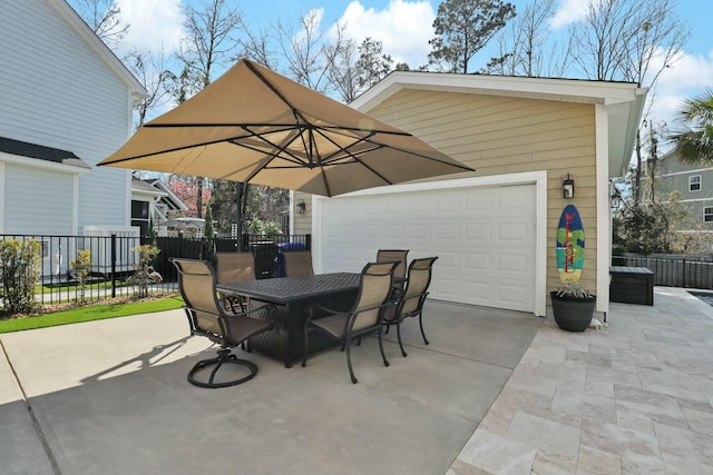 view of patio with concrete driveway, outdoor dining area, fence, and a garage