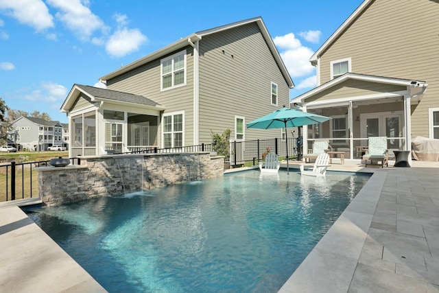 back of property featuring fence, french doors, a sunroom, a fenced in pool, and a patio area