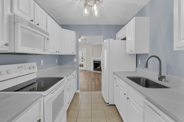 kitchen with white cabinetry, white appliances, sink, and light tile patterned floors