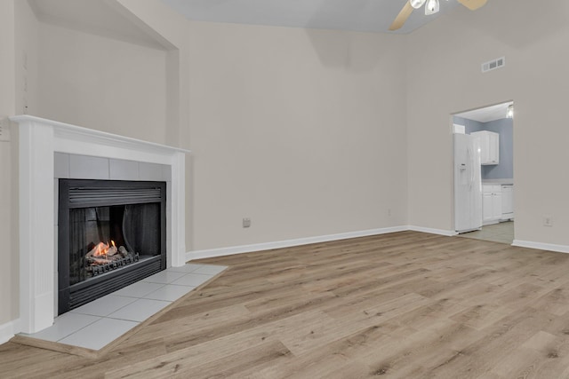 unfurnished living room featuring a fireplace, ceiling fan, and light wood-type flooring